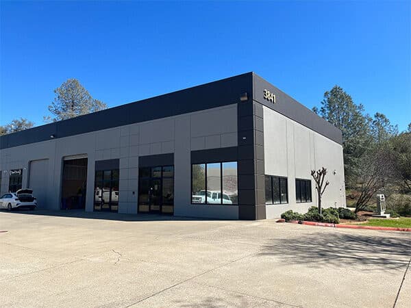 Commercial building exterior with light gray walls and dark trim around windows and garage bays.