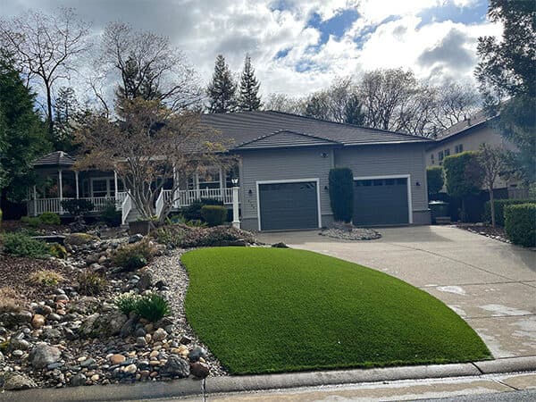 Gray house exterior with white porch railings and two dark garage doors.