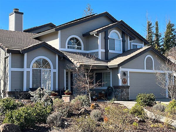 Two-story gray house with contrasting white trim around arched windows and the front porch.