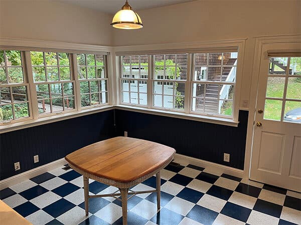 Dining nook with cream upper walls, dark blue wainscoting, and white window trim.