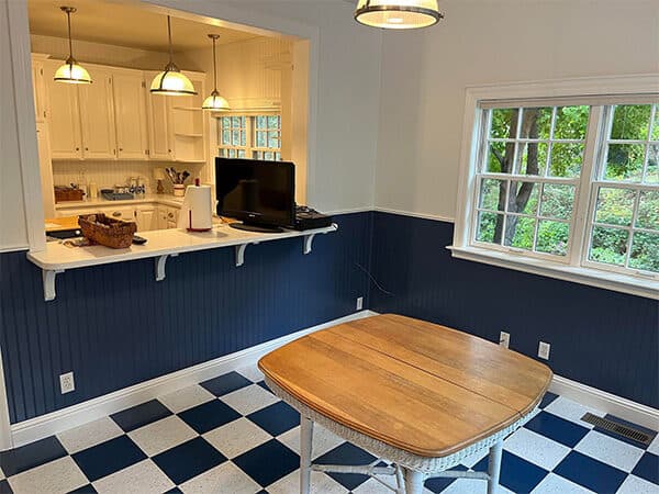 Dining area with blue lower wall paneling, white trim, and a pass-through to a kitchen.