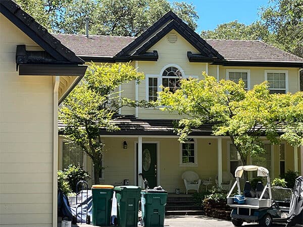 Pale yellow house exterior with dark roof trim and a covered front porch.
