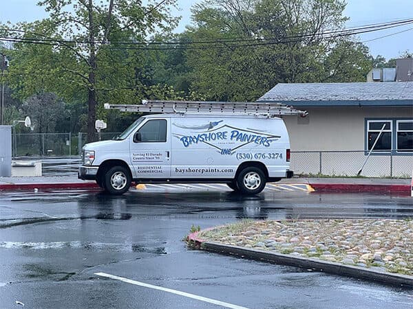 Bayshore Painters service van carrying ladders outside a building.
