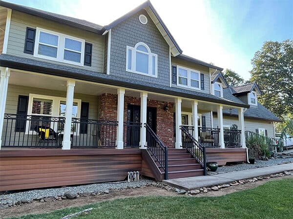 Two-story home with gray siding, white porch columns, and brown front steps.