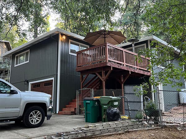 Dark gray house exterior with white window trim and an elevated wood deck.