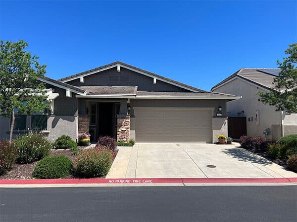 Single-story home with gray exterior paint, a matching garage door, and stone entry columns.
