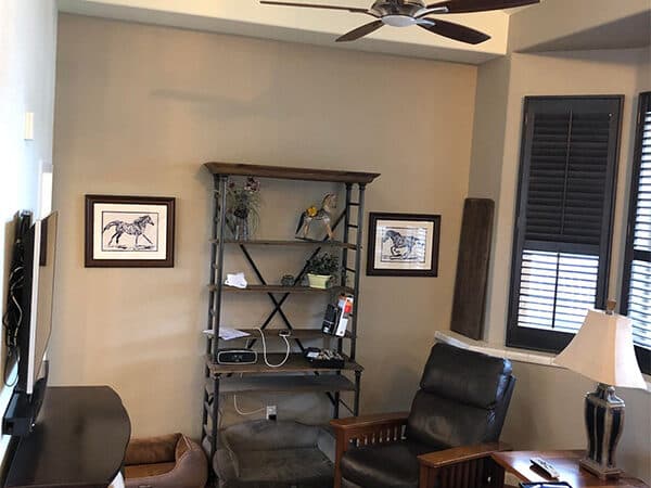 Living room with beige walls, white ceiling trim, and dark window shutters.