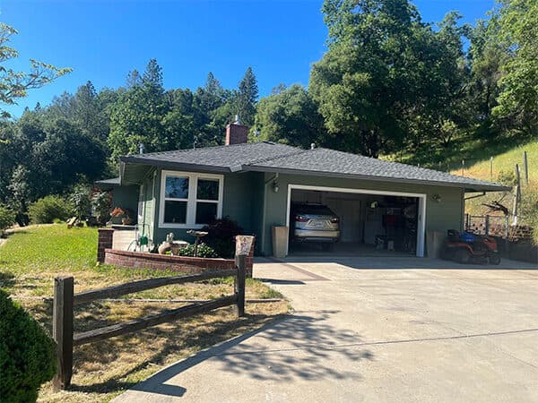 Green house exterior with white window trim and an attached garage.